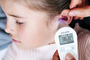 Ohrthermometer Eine Nahaufnahme, wie jemand mit einem Ohrthermometer bei einem Kind am Ohr Fieber misst.