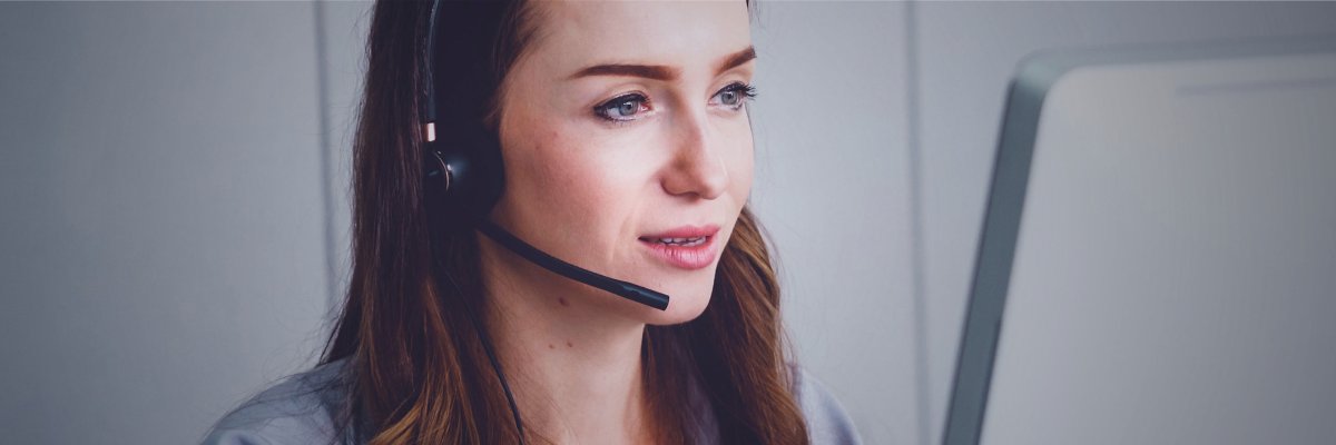 Eine Frau mit dunklen Haaren und Headset welche am sprechen ist 
