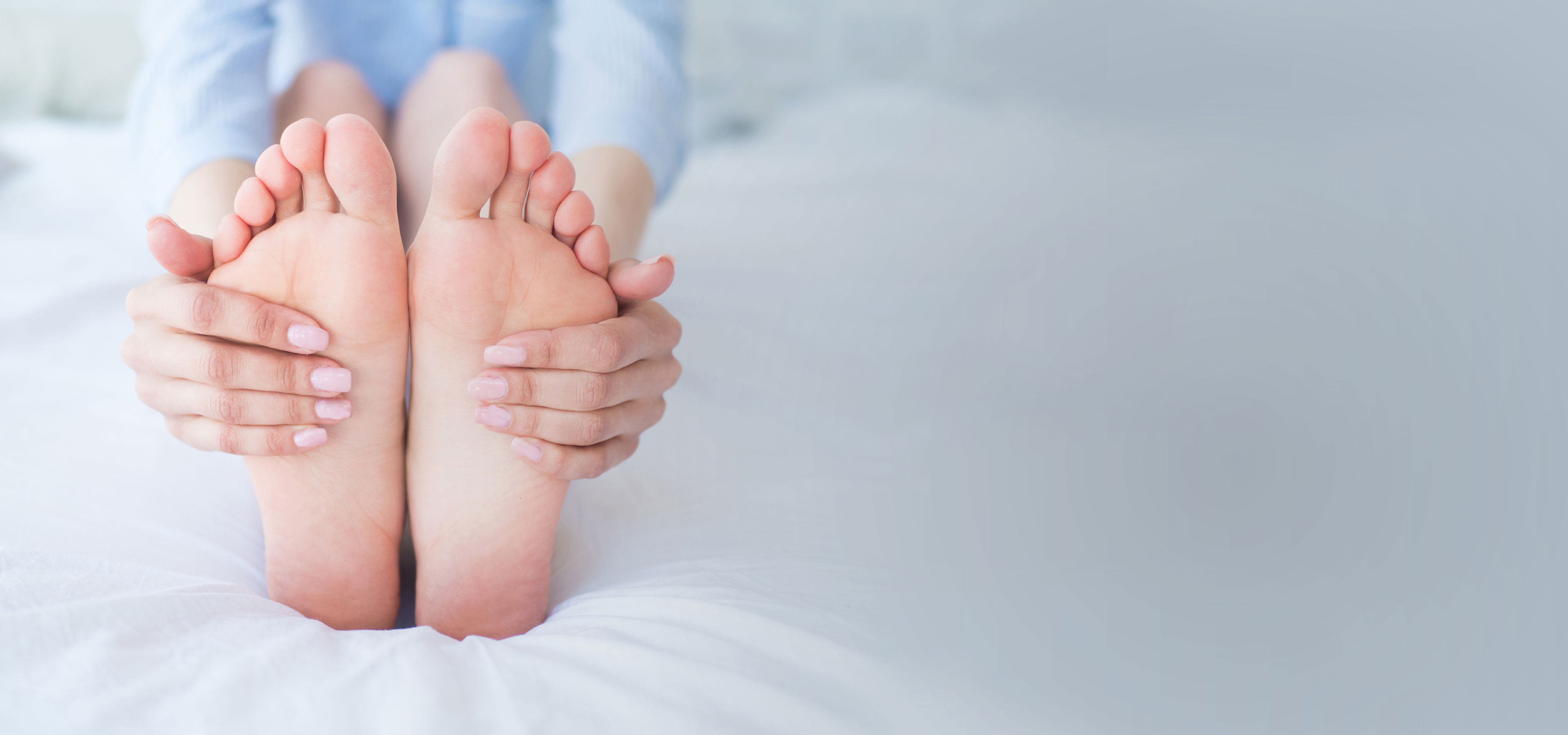 WAS SIND EIGENTLICH WARZEN? Zwei Füße sind zu sehen und eine Frau hält jeweils einen Fuß mit einer Hand fest