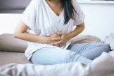 Bauchschmerzen Eine Frau hält sich die Hände vor den Bauch vor Bauchschmerzen