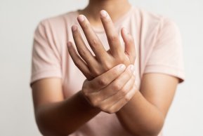 Nahrungsergänzungen Eine Frau in rosa T-shirt hält sich eine Hand fest